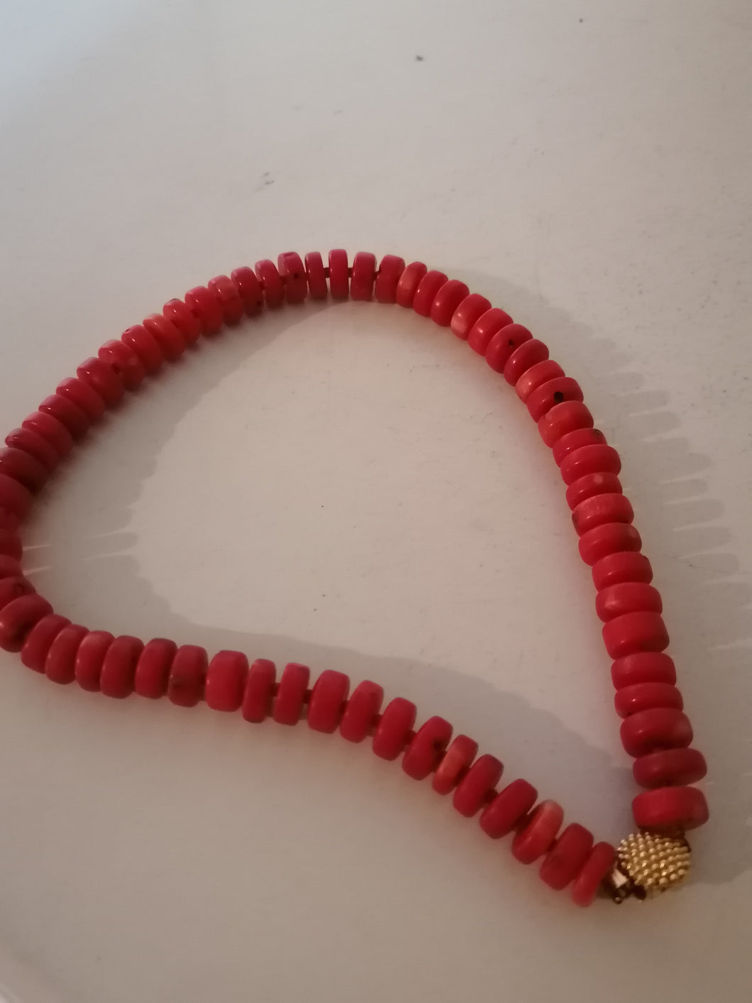 Collier en perle rouge teinté et fermoir doré. 